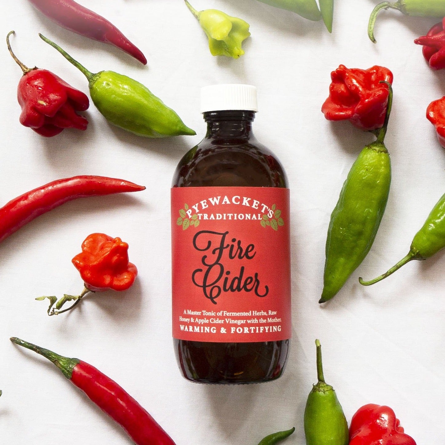 fire cider in amber glass bottle with fresh chillies scattered around