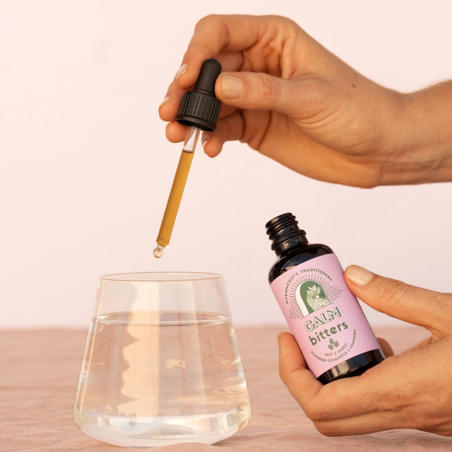 Hand using a dropper to add liquid from a bottle labeled &