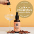 Energy bitters bottle with a dropper being held by a hand, shown next to a coupe glass and cocoa beans on a warm beige background, with a large award badge reading &