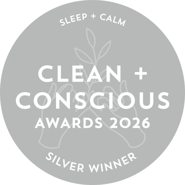 A circular gray badge with white text reading 'SLEEP + CALM', 'CLEAN + CONSCIOUS AWARDS 2026', and 'SILVER WINNER', with a faint botanical and hands illustration in the background.